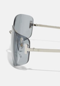 Sunglasses with gray tinted lenses, semi-rimless design, metallic silver accents, and straight temples featuring a logo.