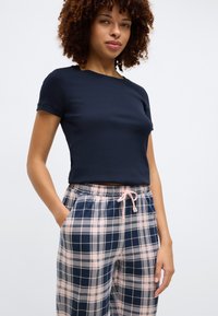 Top de manga curta azul-marinho com textura canelada, combinado com calças de pijama em padrão xadrez nas cores azul-marinho, rosa e cinza, com cintura elástica e cordão.