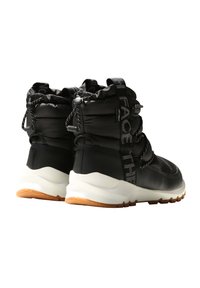 Black waterproof boots with a padded upper, elastic drawstring closure, and a white sole with a gum rubber outsole. Features logo detailing.