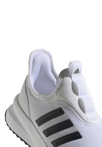 Zapatilla deportiva blanca con parte superior de malla texturizada, suela de goma y tres franjas laterales negras. Cuenta con un cuello acolchado y una lengüeta.