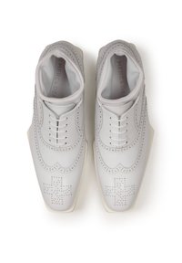 Gray leather shoes with decorative perforations, featuring a unique cross pattern, rounded toe, and a contrasting white sole.
