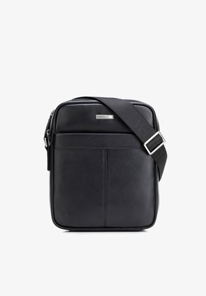 Czarna skórzana torba na ramię z regulowanym paskiem materiałowym, przednią kieszenią i srebrną, prostokątną tabliczką z logo marki.