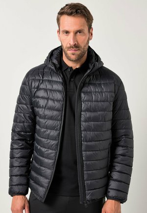 Schwarze gepolsterte Jacke mit Kapuze, mit horizontalen Steppnähten, Reißverschluss und einer glatten, glänzenden Oberfläche. Getragen über einem schwarzen Hemd.