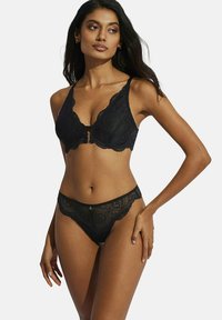 Soutien-gorge en dentelle noire et string assorti avec des bords festonnés et des motifs floraux élaborés, présentant un détail central de crochet sur le soutien-gorge.