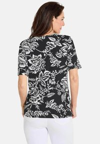 Zwarte top met korte mouwen en een wit bloemmotief, met een zachte textuur, een ronde halslijn, een getailleerde pasvorm en een gebogen zoom.