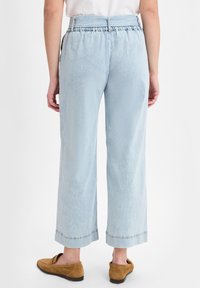 Lichtblauwe wijde broek met een gerimpelde tailleband, een gestructureerde stof en contrasterende stiksels aan de zoom, in combinatie met tan instappers.
