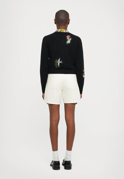Black sweater with colorful floral embroidery on the back, paired with white shorts. Figures have a relaxed fit and soft texture.