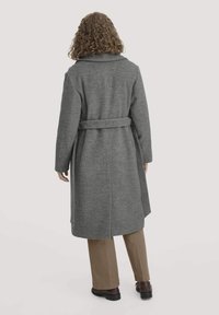 Grauer Wollmantel mit tailliertem Gürtel, weitem Kragen und langen Ärmeln. Mit gerader Silhouette, die knapp unter die Knie reicht.