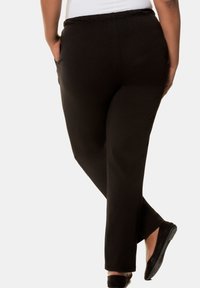 Zwarte, rekbare stofbroeken met een ontspannen pasvorm, voorzien van zijzakken en een elastische tailleband. Gladde textuur, enkel-lange uitvoering.