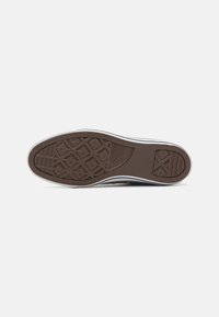 Brown rubber shoe sole with textured grip pattern, featuring white side accents and a rounded toe design.