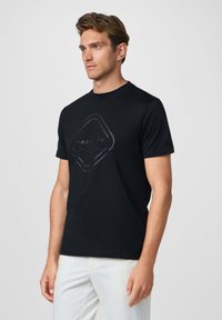 Camiseta negra con un logo gráfico en gris oscuro en el centro. Corte estándar con mangas cortas y cuello redondo. Textura de tela suave.