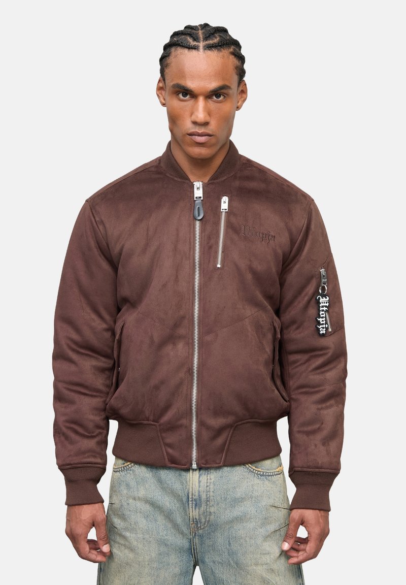 Giacca bomber in suede marrone con polsini e orlo a costine, dotata di una chiusura con zip e tasche laterali. Logo ricamato sulla manica.