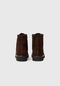 Bruna mockaboots med slät yta, dragkedjestängning och tjock gummisula med djupa mönster för bra grepp.