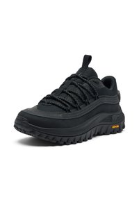 Musta vaelluskenkä, jossa on tekstuuripinta, paksu kumipohja, erottuvat nauhat ja oranssi Vibram-logo.