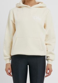 Felpa color crema realizzata in tessuto morbido, con tasca frontale e cappuccio. Riporta la scritta "Good Vibes Only" in bianco.