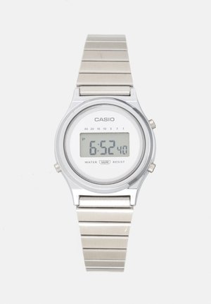 Digitalni Casio sat sa srebrnim metalnim remenom i okruglim kućištem. Ima bijelo lice s LCD zaslonom, na kojem je prikazano vrijeme 6:52. Vodootporan.