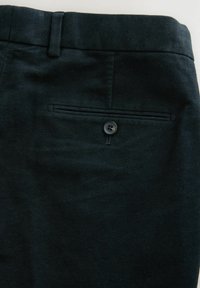 Dunkelblaue Wollhose mit glatter Textur, ausgestattet mit einer Gesäßtasche mit Knopfverschluss und einem taillierten Bund.