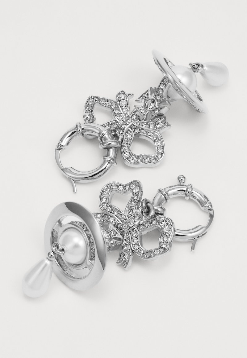Orecchini in argento con design a farfalla decorati con strass, una perla centrale e un accento a goccia di perla. Finitura in metallo liscia e lucida.