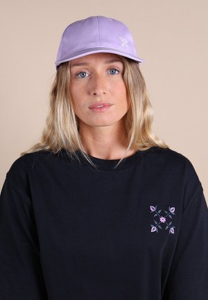 Casquette de baseball violette et t-shirt noir avec un motif floral rose et marine sur la poitrine gauche. Coupe simple et structurée.
