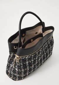 Sac à main en tweed noir et blanc avec un motif texturé, fermeture éclair dorée et accents en cuir noir. Comprend deux poignées solides et un intérieur spacieux.