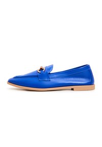 Mocassin plat en cuir bleu avec semelle beige et petit détail de boucle dorée sur le dessus, vu de côté sur fond blanc.