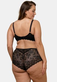 Ensemble de lingerie en dentelle noire avec des motifs floraux délicats. Bretelles ajustables, bords festonnés et coupe confortable, mettant en valeur un design taille haute.