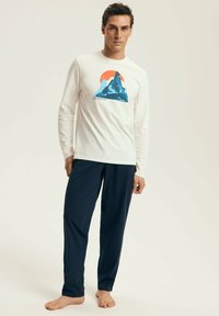 Long-sleeve white shirt with a blue mountain graphic and orange sun, paired with dark blue pants, made from lightweight fabric.