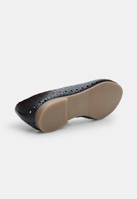 Ballerina nera perforata con punta tonda e suola beige flessibile. Presenta una finitura liscia e un sottile motivo a intaglio per la traspirabilità.