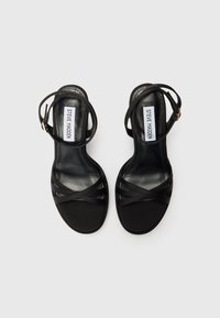 Juodos dirželinės sandalos su elegantišku atviru pirštu. Pagamintos iš lygios odos, su kryžminiais dirželiais ir kulkšnies dirželiu, užtikrinančiu tvirtą prigludimą.