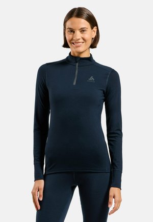 Navy blue long-sleeve top with a half-zipper and a high collar. Features a logo on the chest, made of smooth, stretchy fabric.