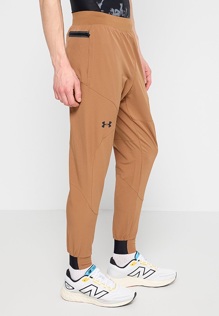 Pantalones deportivos marrones con piernas ajustadas, cinturilla elástica y bolsillo con cremallera. Fabricados en un material ligero y transpirable con detalles de costura.