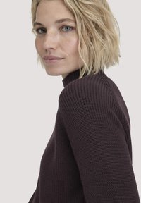 Maglione a maglia in un profondo bordeaux con colletto alto, caratterizzato da costine testurizzate lungo le spalle e le maniche per un tocco di dettaglio in più.