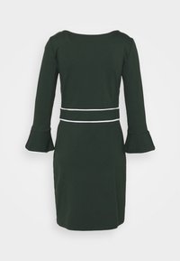 Robe vert foncé longueur genou avec de longues manches évasées et deux bandes blanches horizontales autour de la taille, vue de dos.