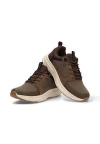 Zapatillas deportivas marrones con parte superior de malla y superposiciones texturizadas, que cuentan con una suela acolchada en beige con acentos moteados. Incluye cordones y ojetes.