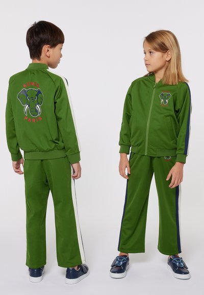 Completo tuta verde con grafica di un elefante, giacca con zip e strisce laterali, e pantaloni abbinati con dettagli laterali a contrasto.