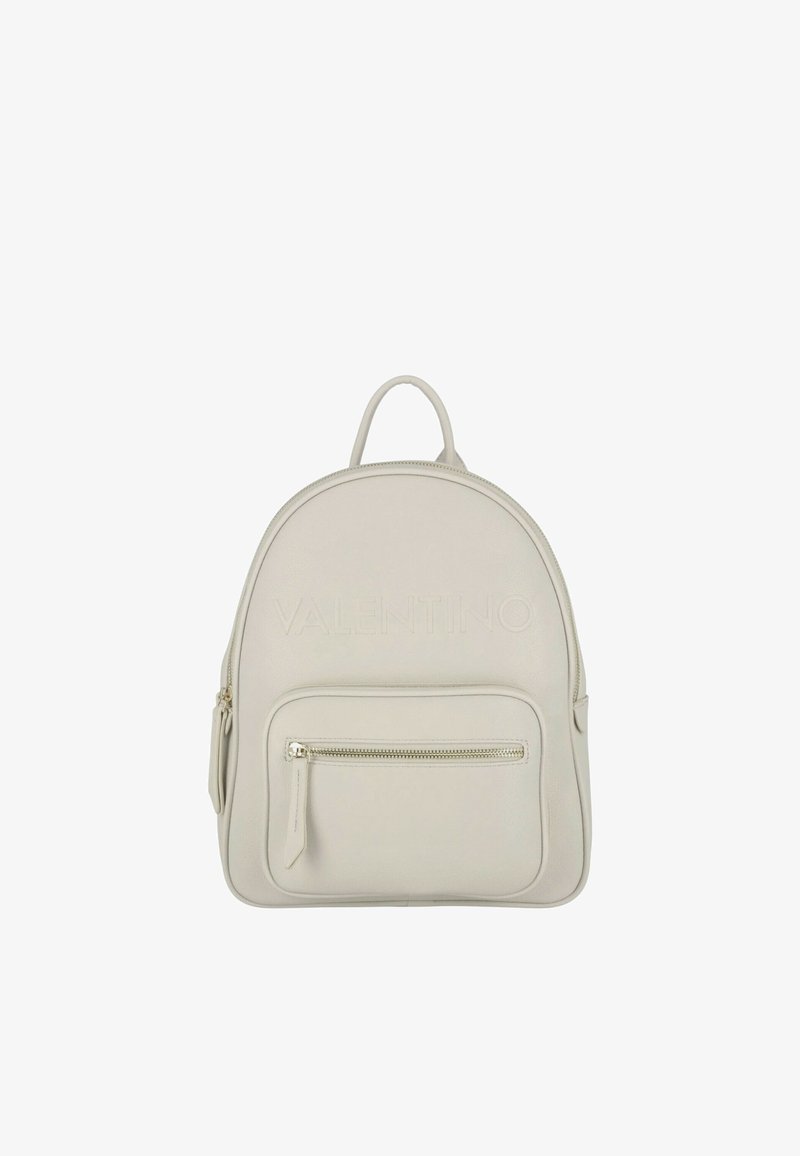 Mochila de cuero crema con forma redondeada, logo en relieve en la parte frontal, bolsillo con cremallera y asa superior. Diseño minimalista con una textura sutil.