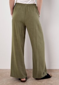 Pantaloni larghi, verde oliva, realizzati in tessuto leggero; presentano una vita elastica e tasche laterali; design a gamba larga.