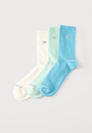 Tres calcetines de canalé hasta la tripa en blanco, verde menta y azul, cada uno con un pequeño logo cerca de la parte superior y texto en las puntas.