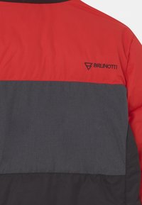 Chaqueta acolchada roja y gris con un tejido texturizado, diseño de bloques de color y un logo negro en el lado superior izquierdo.