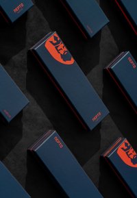 Marineuhrkasser med røde accenter, prydet med en dristig grafik og branding, arrangeret pænt på en sort overflade.