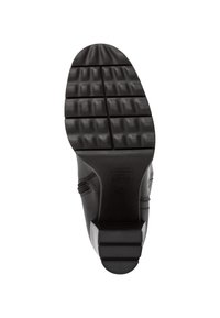 Suela de zapato de goma negra con un patrón de relieve texturizado. Presenta ranuras horizontales y verticales para una mejor tracción y durabilidad.