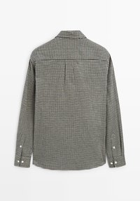 Camicia a maniche lunghe realizzata in tessuto a quadretti nero e bianco. Presenta un colletto classico, polsini con bottoni e un giogo sul retro per la struttura.