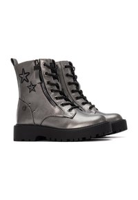 Botas tobilleras de color plateado metálico con cordones y cremallera lateral. Decoradas con bordado de estrellas negras, presentan una suela de goma negra gruesa.