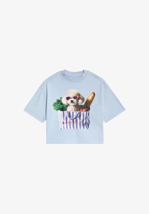 Lichtblauw t-shirt met een hondenafbeelding met een zonnebril, gecombineerd met een roze-wit gestreepte gelaagde rok. Tekst: "French Riviera Marseille."