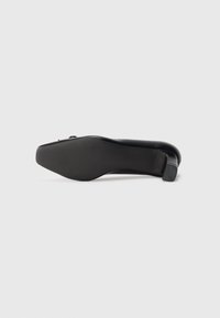 Black high-heeled shoe featuring a smooth, glossy finish, round toe, textured sole, and a slender heel with a non-slip grip.