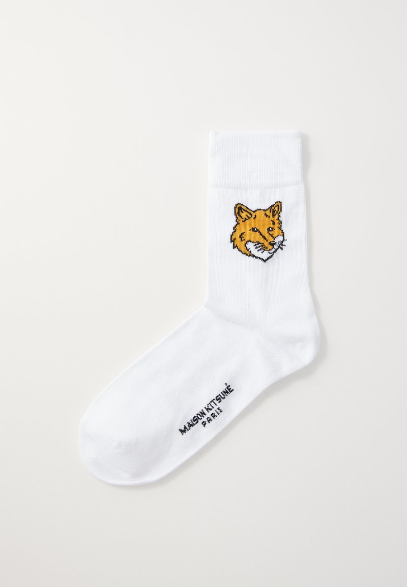 Valge puuvillane sokk, mille küljes on tikitud oranž rebasepea kujutis pahkluul. Brändi nimi "MAISON KITSUNÉ PARIS" on trükitud varba lähedale.