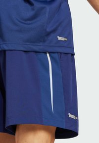 Pantalones cortos azul marino con un patrón texturizado, que cuentan con un acento de rayas blancas y un logotipo "ClimaCool". Fabricados con un material ligero y transpirable.