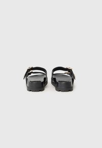 Sandale negre cu două catarame ajustabile, talpă plată și textură pentru aderență. Design minimalist cu finisaj din material neted.