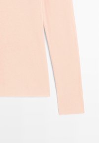 Helles rosa Langarmoberteil aus weichem Stoff, mit geradem Schnitt, glatter Textur und ohne Muster oder Verzierungen.