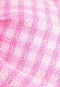 Tessuto leggero e texturizzato in tonalità di rosa con un motivo a zigzag, caratterizzato da sfumature alternate e bordi morbidi e arricciati.